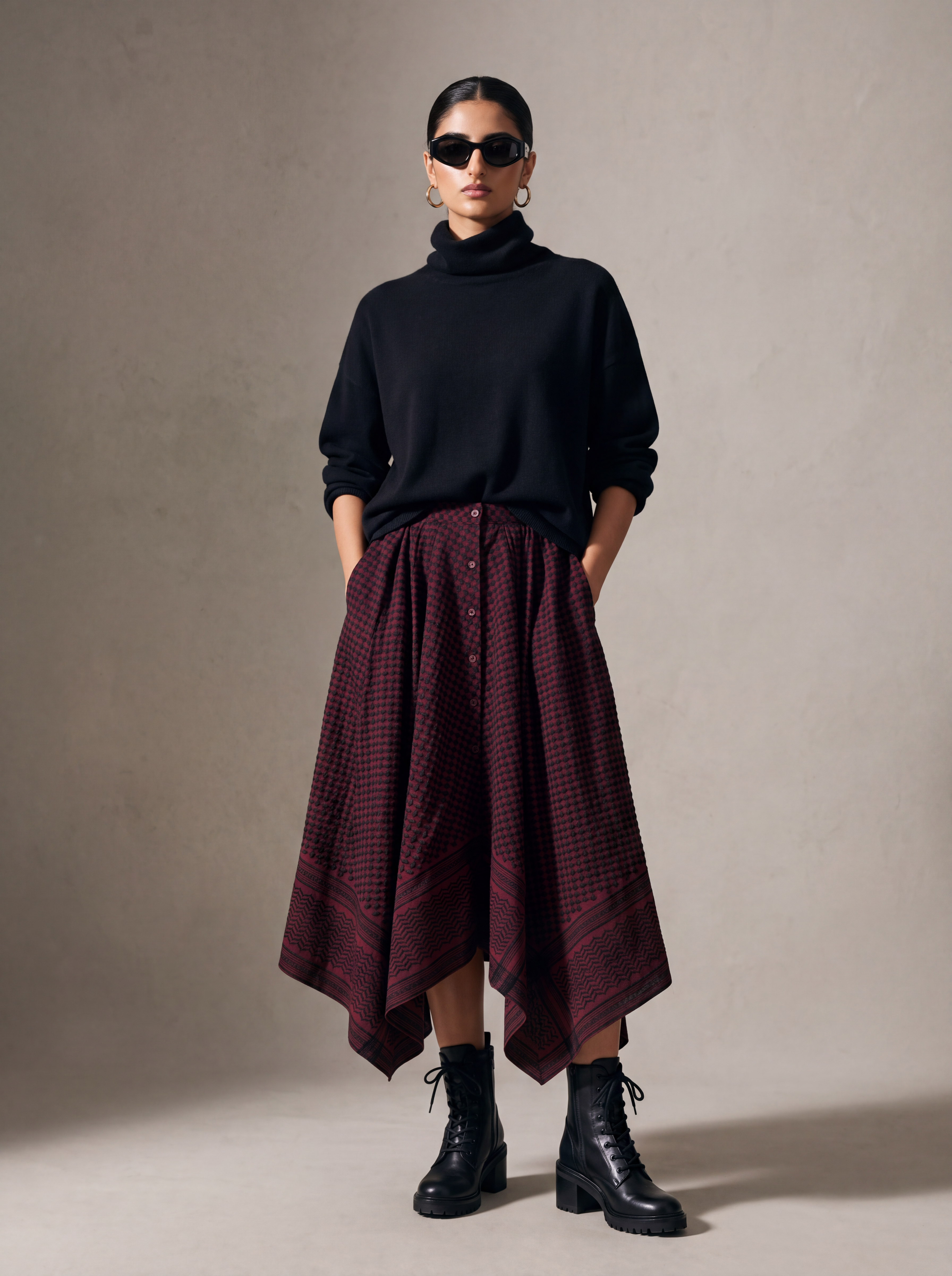 Model wearing burgundy and black keffiyeh embroidered asymmetric maxi skirt